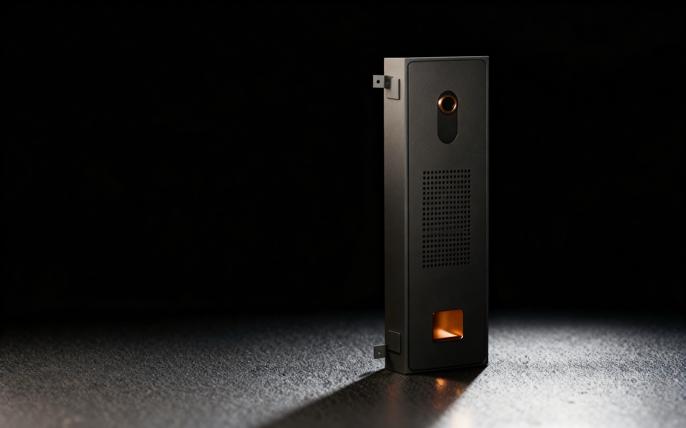 The Koja Tech Bar standing upright in a dark studio: a camera lens at the top, a speaker grille in the middle and a softly lit treat opening at the bottom